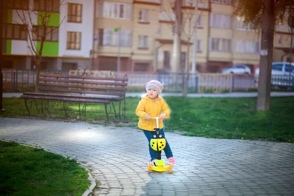 청바지를 자켓을 소녀는 스쿠터를 도시의 놀이터를 달립니다 — 스톡 사진