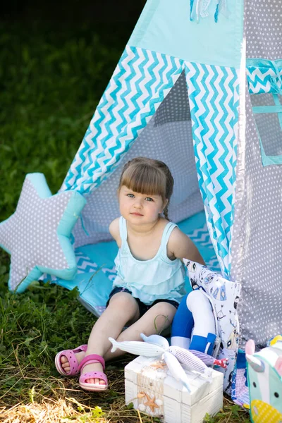 Kleines Süßes Mädchen Sitzt Sommer Mit Spielzeug Einem Stoffhaus Auf lizenzfreie Stockfotos