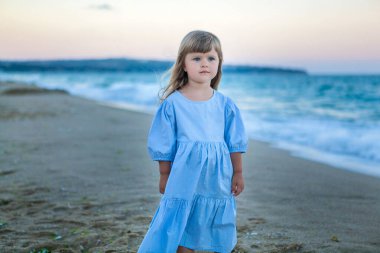 Gün batımında deniz kıyısında mavi elbiseli tatlı bir kız.