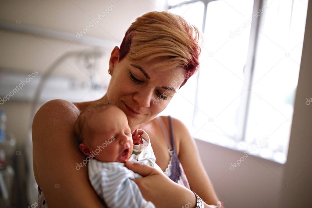 Mother holding her newborn baby in maternity clinic