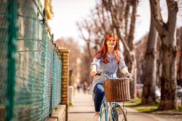 年轻微笑的妇女骑自行车在城市 — 图库照片