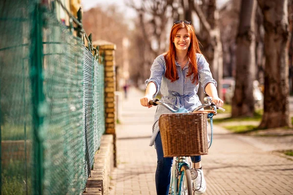 在城市白天享受自行车的年轻微笑的妇女 — 图库照片