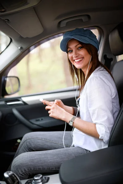 妇女在汽车用耳机拿着手机 — 图库照片