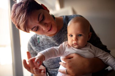 Holding ve şirin bebeği sarılma mutlu anne-çocuk gürlemesi elleri. Mutlu aile yaşam kavramı