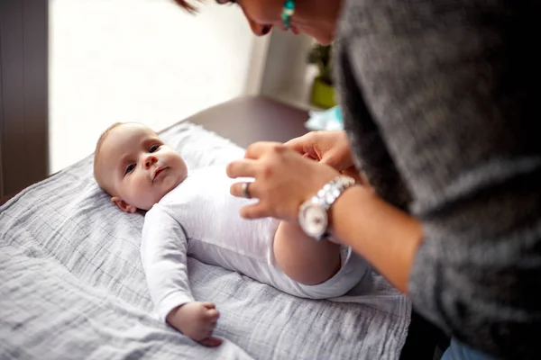 ベッドに横になっている彼女の笑顔のかわいい赤ちゃん男の子と遊んで幸せママ — ストック写真