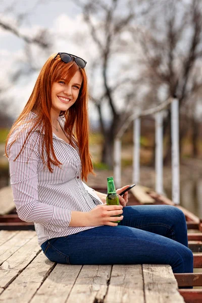 微笑んでいる女の子を楽しんで 自然の中をリラックスと川でビールを飲んで — ストック写真