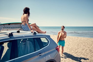 Sağlıklı aktif yaşam tarzı. Sörf. Yaz tatili. Aşırı spor. Arabada oturan ve sörf için hazırlanıyor gülümseyen sörfçü kız