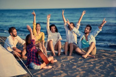 Yaz, tatil, tatil, müzik, mutlu insanlar kavramı grup gülümseyen arkadaşıyla birlikte eğleniyor sahilde gitar ile