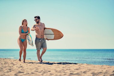 Sahilde yürüyüş sörfçü gülümseyen genç çift