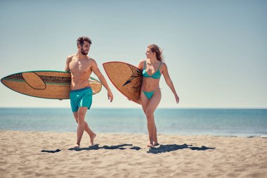 Sağlıklı aktif yaşam tarzı. Sörf. Genç erkek ve kadın sörfçü olacak birlikte plajda sörf için 