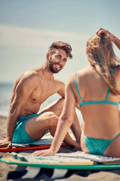 ビーチ ビーチでサーフボードを持つスポーティな人々 極端なスポーツや休暇の概念の高い波を待っている若いサーファー夫婦 — ストック写真