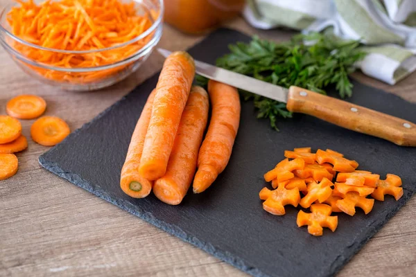 cutting fresh carrots on slice for salad on chopping board in the kitchen