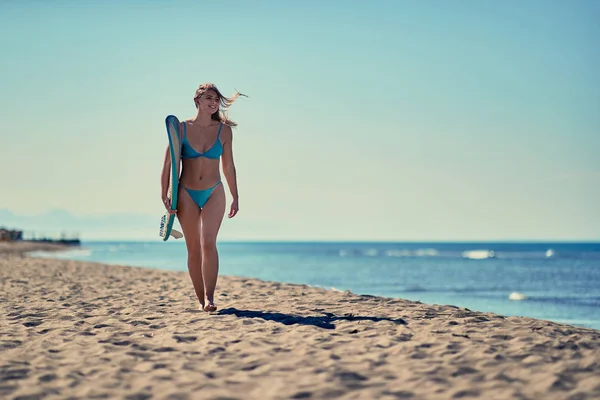 砂浜のビーチでボードと歩いているサーファー少女の笑みを浮かべてください ウォーター スポーツ 健康的なアクティブなライフ スタイル サーフィン 夏休み 極端なスポーツ — ストック写真