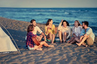 Grup Genç arkadaşlar gitar ve şarkı bir şarkı deniz kumsalda oynarken ile birlikte rahatlatıcı