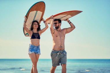 Genç çift sahilde yürüyüş ve having fun yaz aylarında sörfçü gülümseyen