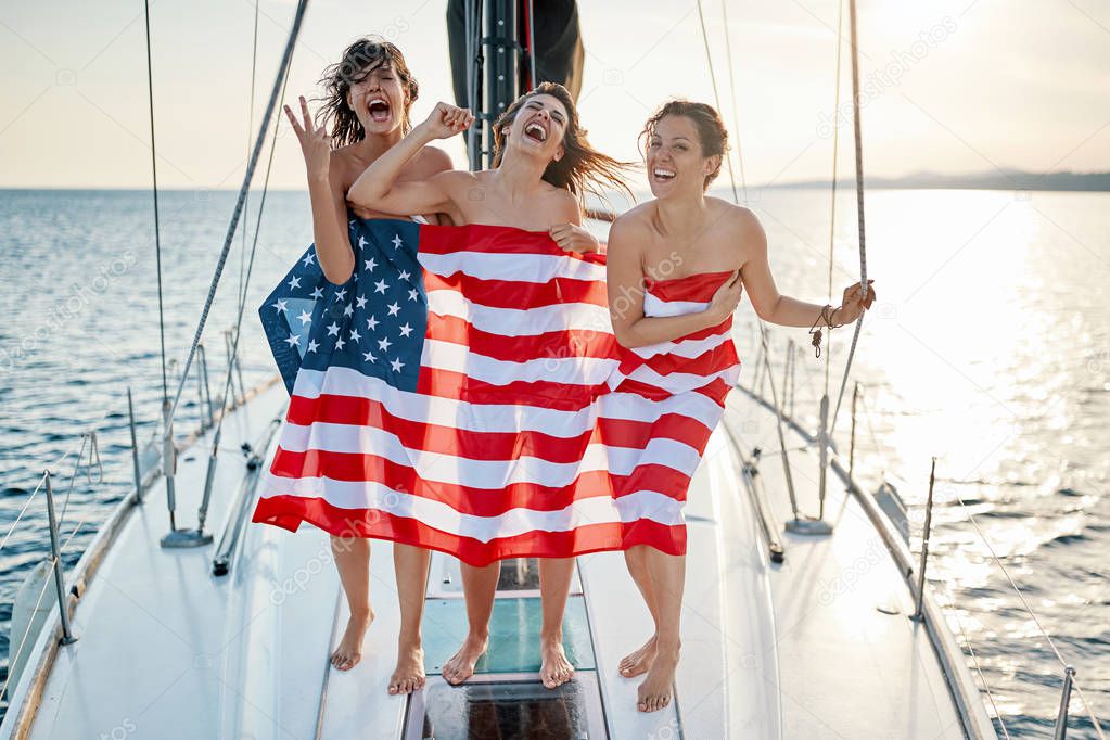 Sexy happy young girls on the yacht in American flay