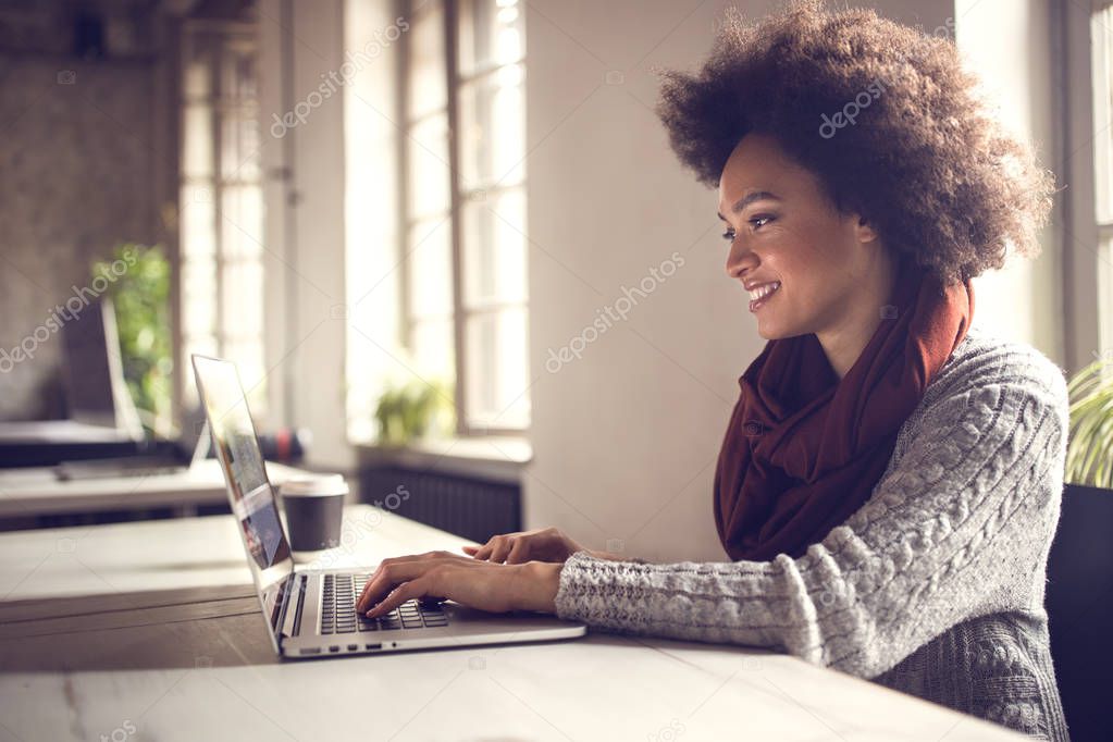 Young Afro-American female working on computer on workplace