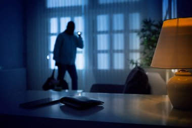 Burglar or intruder inside of a house or office with flashlight clipart