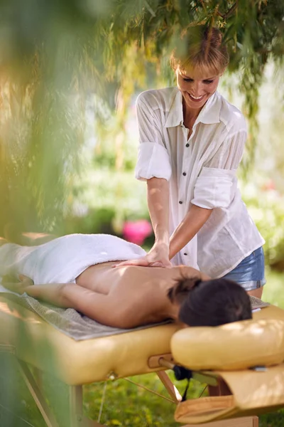 按摩疗法 医疗保健概念 躺在按摩床上的年轻妇女接受了一个专业的按摩师治疗自然 — 图库照片