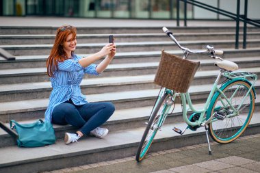 Genç kadın şehirdeki merdivenlerde otururken fotoğraf yapma