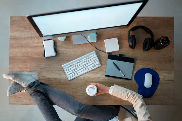 オフィスで机の上の足を保持しながら休憩を作る創造的な Web デザイナー女性のトップ ビュー — ストック写真