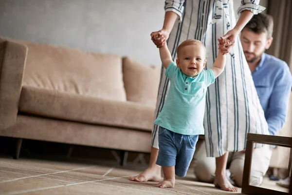 彼らの笑顔の子男の子の第一歩を歩く若い母と父の自宅学習します — ストック写真