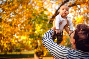Küçük bebek oğlu ile güneş sıcak sonbahar günü parkta oynarken mutlu genç anne. Mutlu aile kavramı