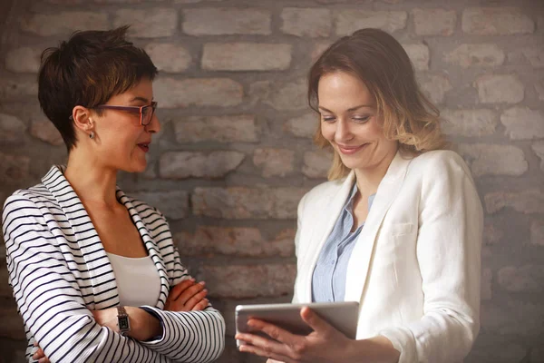 Twee Vrouwen Kijken Ipad Praten Bedrijf Binnen — Stockfoto
