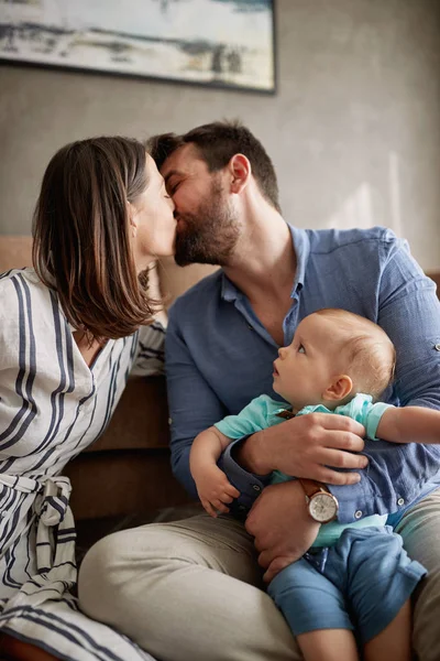 快乐的爸爸妈妈抱着可爱的小男孩在家接吻 — 图库照片