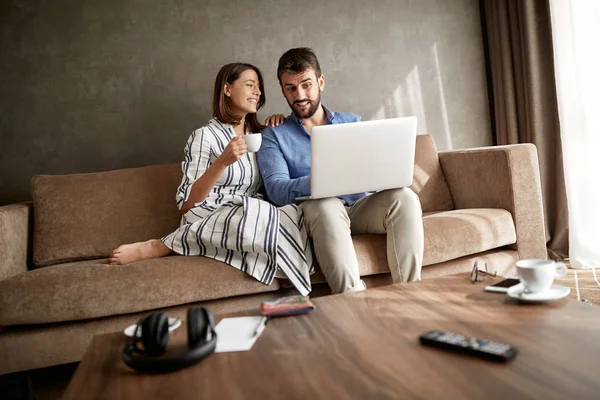 微笑的年轻夫妇在笔记本电脑在早上与咖啡的乐趣 — 图库照片