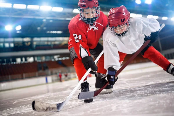 young children hockey player handling puck on ice