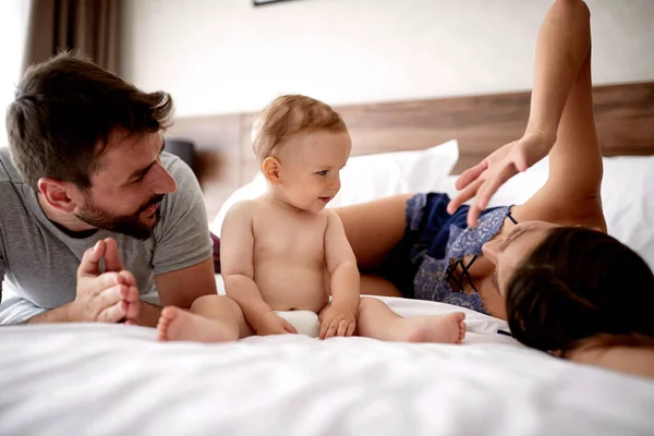 Family with kid in the morning. Young mother, father and baby child on a white bed