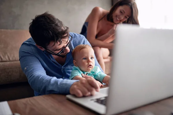 Młody Człowiek Pomocą Laptopa Pracy Domu Patrząc Jego Syn Dziecko — Zdjęcie stockowe