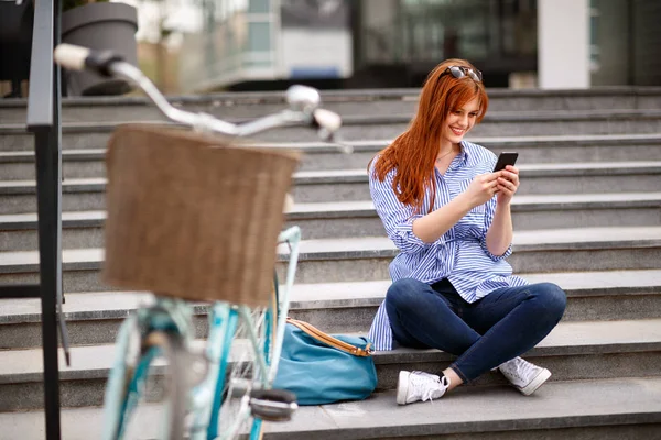 Chica Feliz Mira Teléfono Celular Mientras Está Sentado Las Escaleras — Foto de Stock