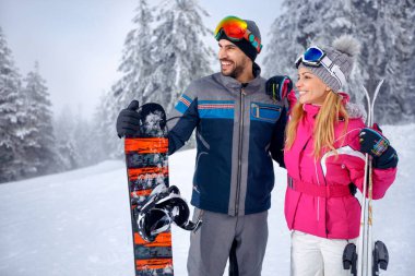 Kayak ve snowboard karlı dağlarda birlikte zevk genç çift gülümseyen