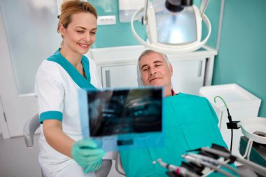 Kadın diş hekimi diş pratikte hastaya çene ve diş röntgeni göster