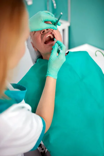 シニアの男性患者が歯科で麻酔を受け取る — ストック写真