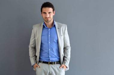 Mavi gömlekli elleri cebinde olan poz genç adam