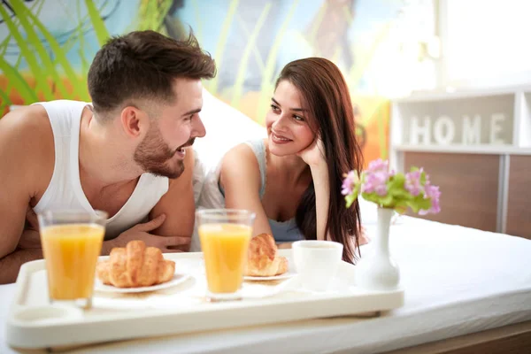 Woman and man in love at morning having breakfast in bed