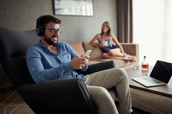 Sorrindo Homem Usa Telefone Para Ouvir Música Relaxar Casa — Fotografia de Stock