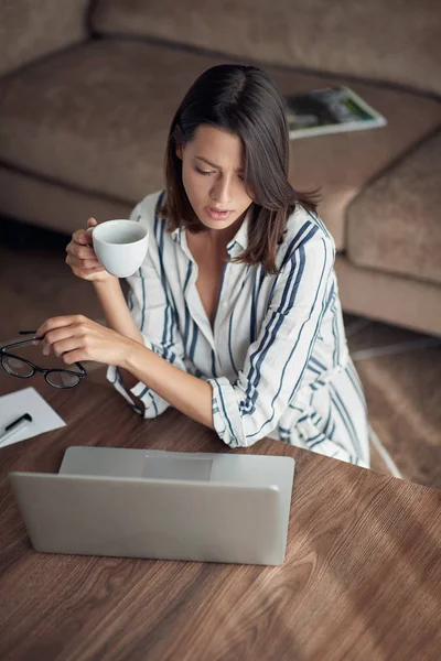 若いビジネス女性のラップトップ コンピューターと家でのんびりとコーヒーを飲む — ストック写真