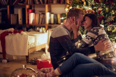 Neşeli genç adam ve kadın hediye birlikte Noel arifesinde zevk ile