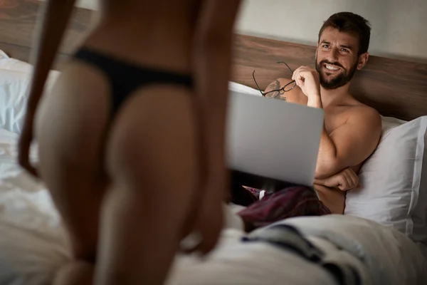 ベッドの上に横たわると下着のセクシーな女性を見て笑みを浮かべて男のセクシーなカップル — ストック写真