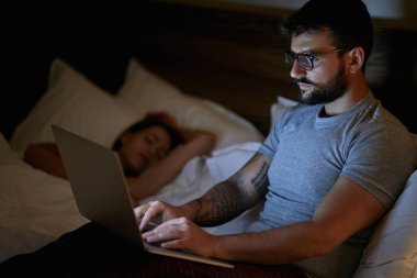 adam evde yatakta yatarken ve laptop ile gece geç saatlerde çalışma