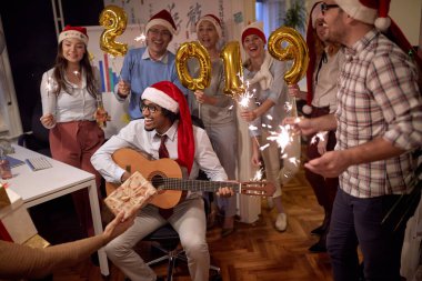 Ofiste Noel partisinde Noel Baba şapkalı grup insanlar mutlu çok ırklı iş