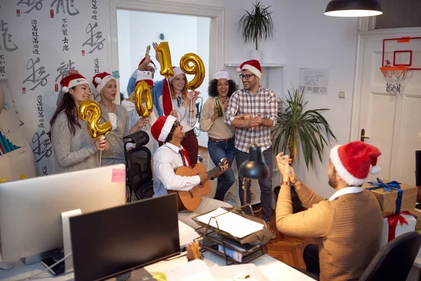 笑顔のビジネス労働者はオフィスでクリスマスパーティーでサンタの帽子で楽しさと踊りを持っています — ストック写真