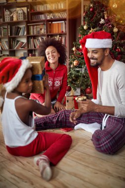 Mutlu genç aile dekore edilmiş Noel ağacı önünde hediye alışverişi