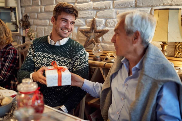 Smiling Son and father together celebrate Christmas at home and giving Christmas present