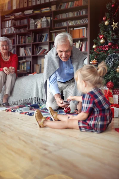 Aranyos Lány Nyitott Karácsonyi Ajándék Egy Díszített Karácsonyi Nagyapám Előtt — Stock Fotó