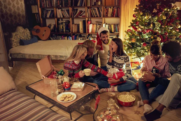 group of happy friends laughing and sharing Christmas gifts